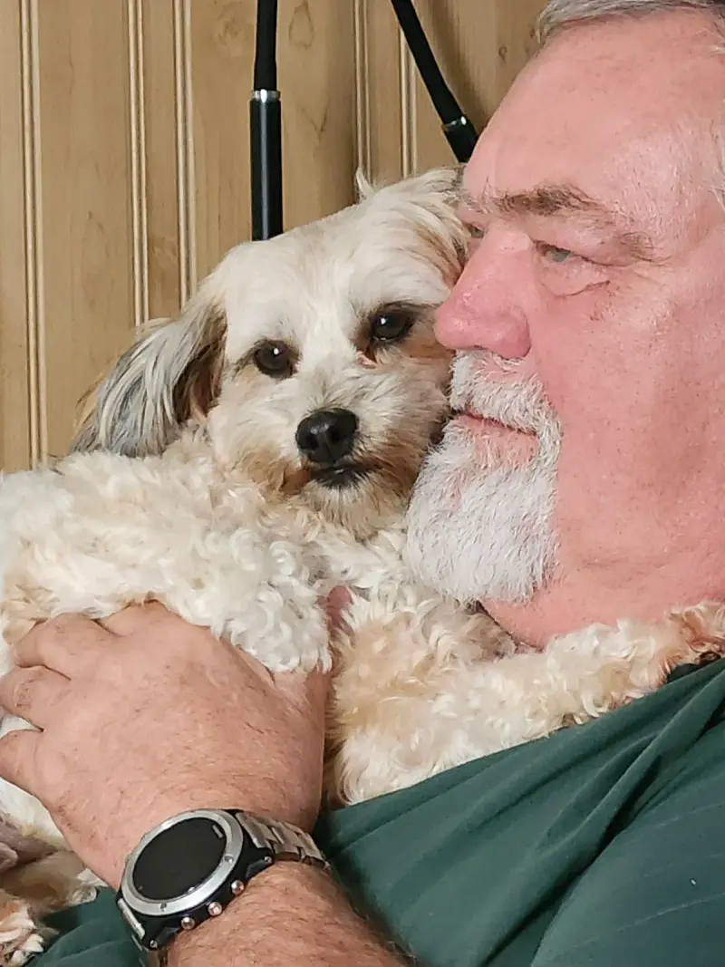 Ellen's husband Ralph having a cuddle with a happy guest dog